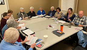 bible study eleven adults sitting around large table during bible study